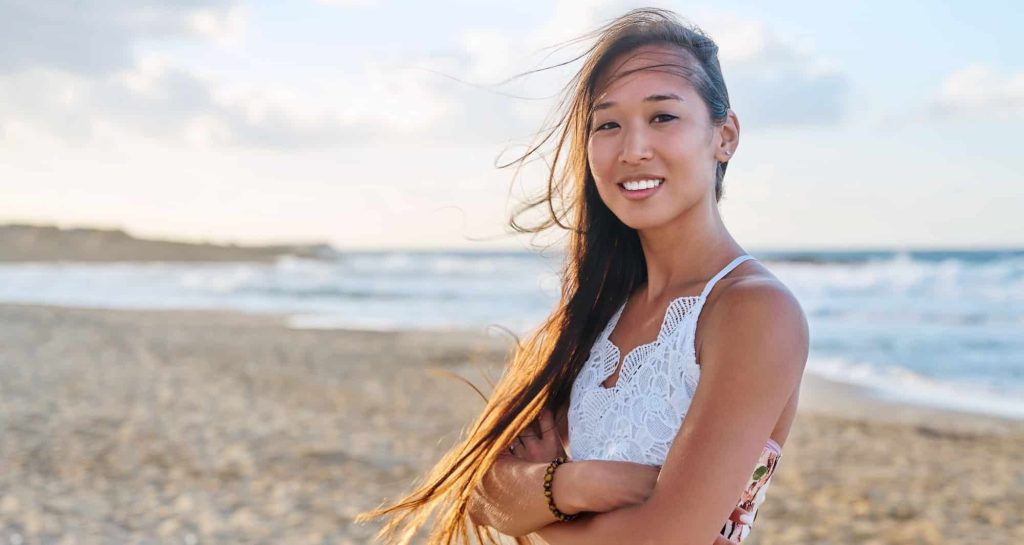 Outdoor portrait of young beautiful asian woman on beach, looking at camera